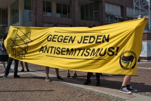 Menschen stehen vor dem dortmunder Rathaus und halten ein Transparent mit der Aufschrift "gegen jeden Antisemitismus"