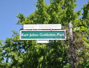 Straßenschild des Kurt-Julius-Goldstein-Park in Berlin, mit einer Kurzvita des Namenpaten.