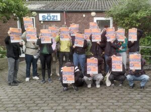 Gruppenbild, auf dem sich die Fotografierten Widersetzen-Plakate vor das Gesicht halten.