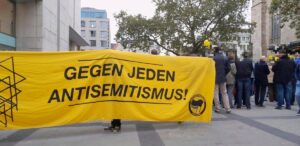 Bild von der Kundgebung zum Jahrestag des 7.10. davor das Transparen "gegen jeden Antisemitismus"