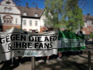 Photo Menschen die hinter Transparenten mit der Aufschrift " Gegen die AfD und Ihre Fans" und "AfD Verbot jetzt" stehen